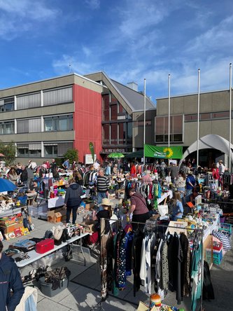 Blick über den vollen Flohmarkt mit Rathaus und dem Verkaufsstand der GRÜNEN im Hintergrund.
